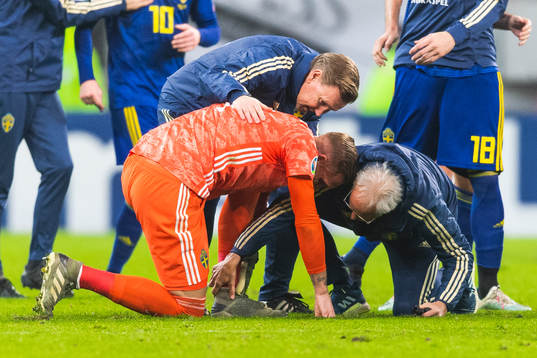 Medical staff attend to goalkeeper Robin Olsen of Sweden