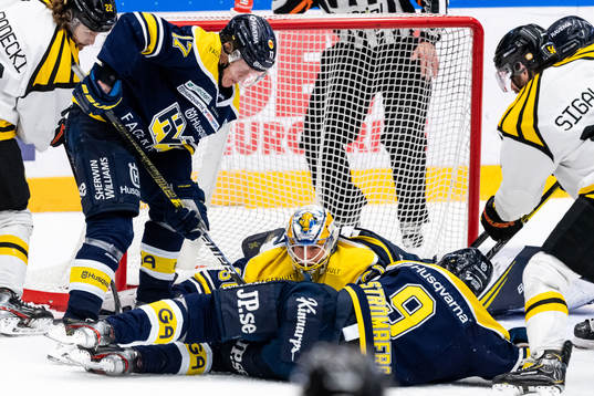 s målvakt Hugo Alnefelt täcker puck med Emil Johansson