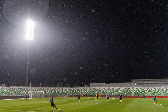 Players are seen warming up in rainfall