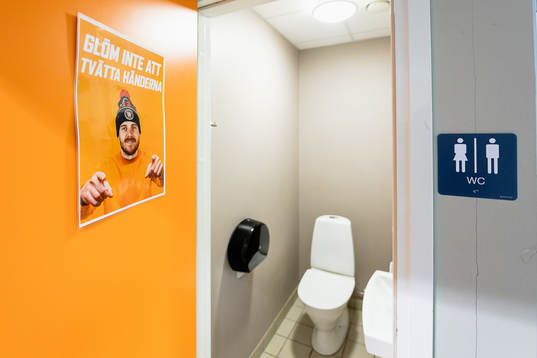 Poster på en toalett med uppmaning att tvätta händer