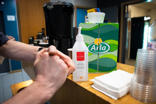 En person spritar sina händer i pressrummet innan