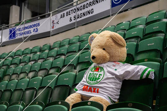 En nallebjörn i Rögle tröja sitter ensam på läktaren