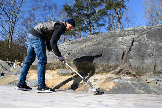 Danny Ervik oljar altanen i sitt hem