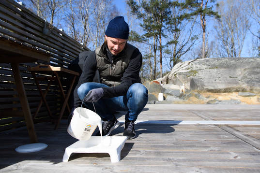 Danny Ervik häller upp olja i ett tråg innan han oljar
