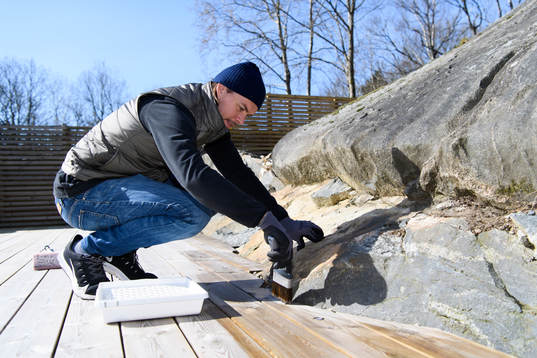 Danny Ervik oljar altanen i sitt hem