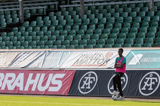 Bollkalle framför tomma läktare innan fotbollsmatchen i