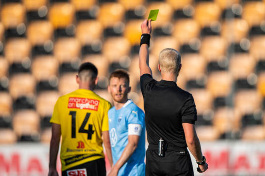 Domare Adam Ladebäck delar ut ett gult kort till Malmö