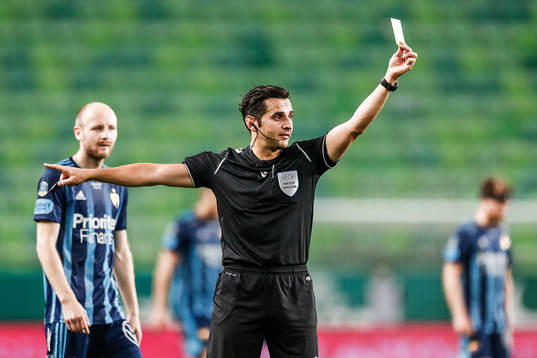 Referee Fedayi San shows a yellow card to Kalle Holmberg of
