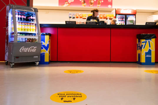 En kiosk med ett klistermärke på golvet som uppmanar