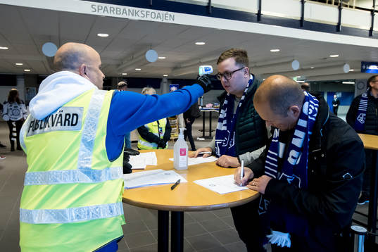 En funktionär mäter temperaturen på åskådare innan