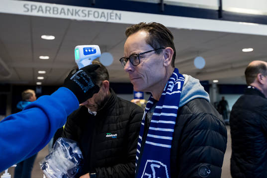 En funktionär tmäter temperaturen på en åskådare innan