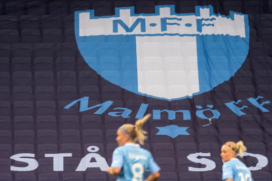 Malmö FFs spelare framför Malmö FFs klubbmärke
