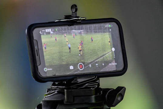 En mobiltelefon livesänder fotbollsmatchen i Division 3