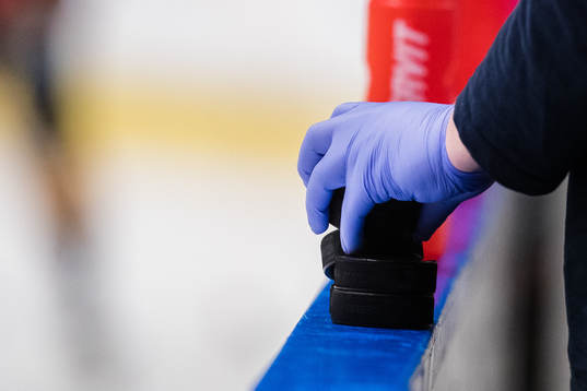 En hand med gummihanske håller i puckar innan