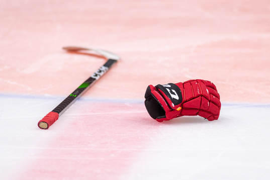 En klubba och en hockeyhandske ligger på isen