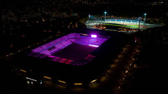 Exteriör vy över Eleda Stadion med rosa ljus på skyltar,
