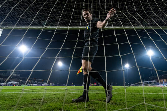 En assisterande domare kollar nätet i fotbollsmålet