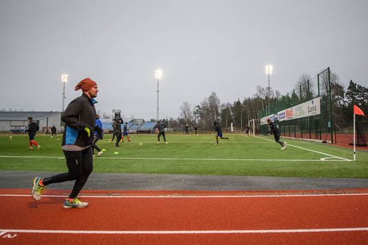 En motionär framför Karlslunds spelare som värmer upp