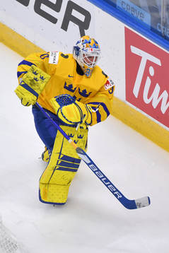 Hugo Alnefelt of Sweden clears the puck around the boards