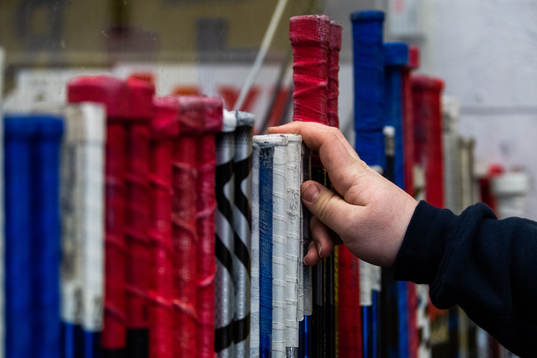 En hand sträcker sig mot hockeyklubbor i båset