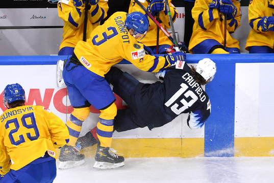 Tobias Björnfot of Sweden hits Cole Caufield of USA