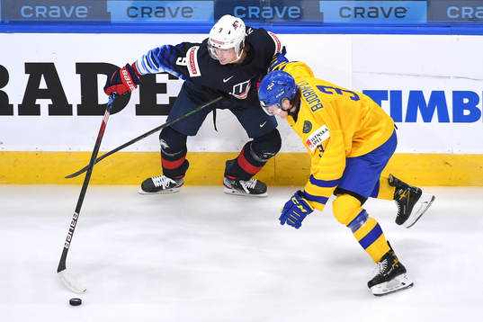 Tobias Björnfot of Sweden and Trevor Zegras of USA battle