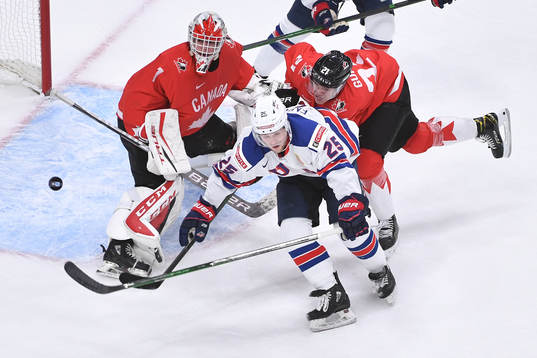 Devon Levi of Canada watches the puck fly through the air