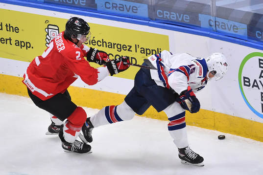 Braden Schneider of Canada battles for the puck in the