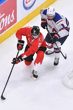 Connor McMichael of Canada keeps the puck away from Jake