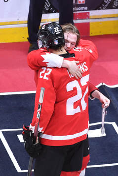 Bowen Byram of Canada hugs teammate Dylan Cozens