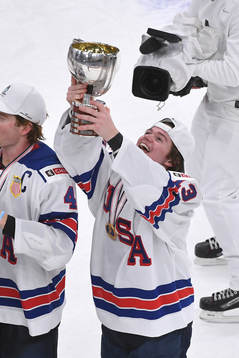 Cole Caufield of USA holds up the championship trophy
