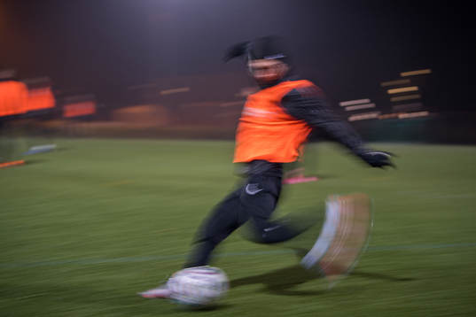 En fotbollsspelare i rörelseoskärpa sparkar på en boll