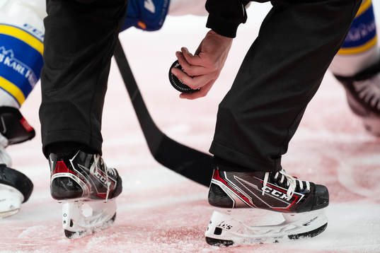 Linjedomare Johan Löfgren med pucken vid tekning
