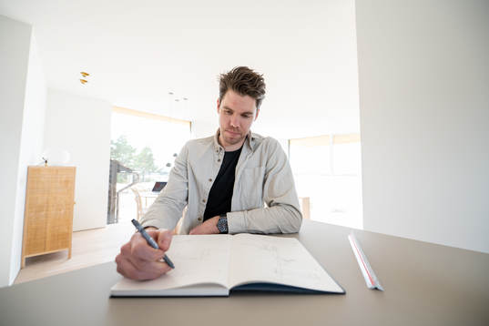 Linus Fernström sitter och skissar i en skissbok han fått