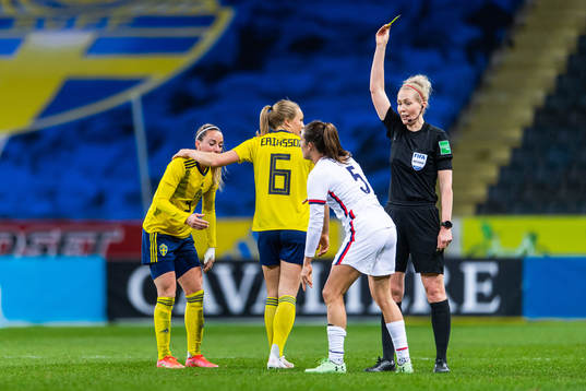 Kelley O’Hara of USA receives a yellow card from referee
