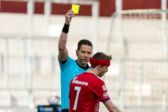 Domare Martin Strömbergsson delar ut ett gult kort till