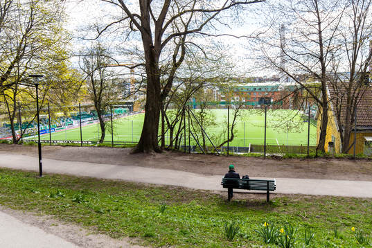 En man i Hammarbykeps sitter på en parkbänk utanför