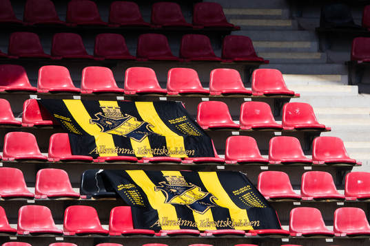 Tomma läktare med AIK-flaggor innan fotbollsmatchen i