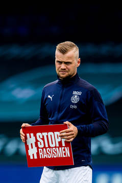 Herman Stengel of Strømsgodset holds a Stopp Rasismen sign
