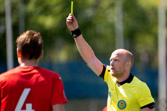 Domaren Patrik Eriksson visar ett gult kort