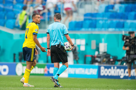 Robin Quaison of Sweden and referee Michael Oliver