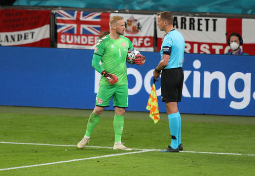 Goalkeeper Kasper Schmeichel speaks to the assistant referee
