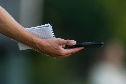 En reporter håller i block och telefon