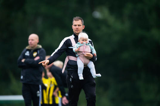 Pappa med bebis i sele coachar sitt lag i matchen för