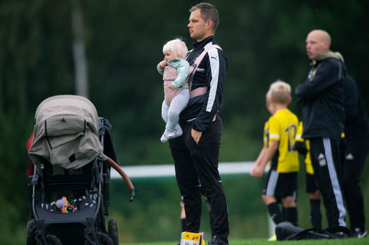 Pappa med bebis i sele coachar sitt lag i matchen för