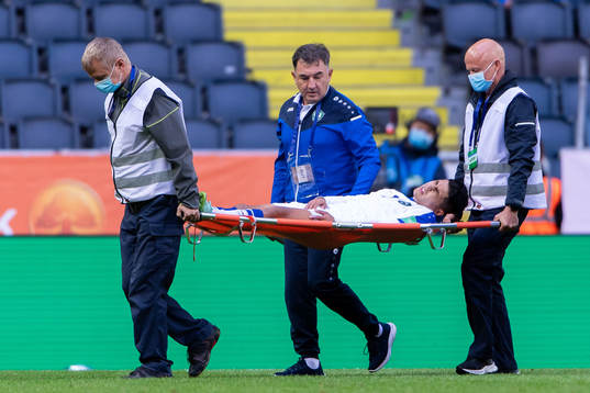 Farrukh Ikromov of Uzbekistan is carried off the pitch