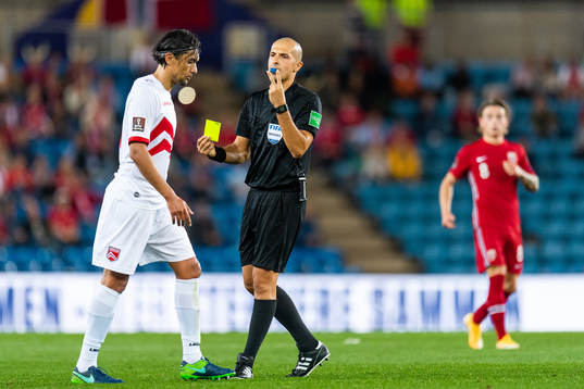 Julian Valarino of Gibraltar receives a yellow card from