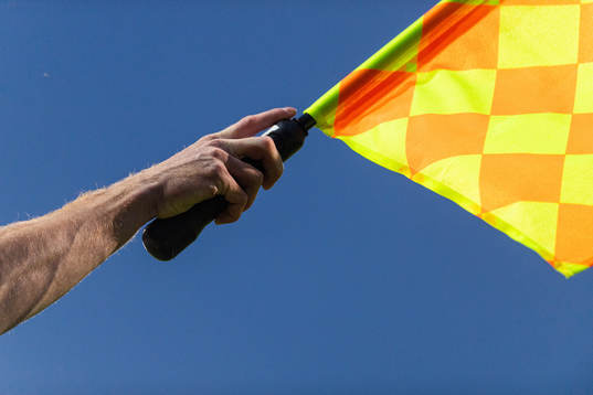 En assisterande domares hand håller en flagga