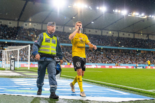 En ordningsvakt eskorterar Mjällbys Elias Andersson av