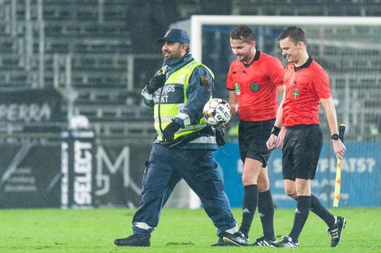 Domare Joakim Östling eskorteras av en ordningsvakt i